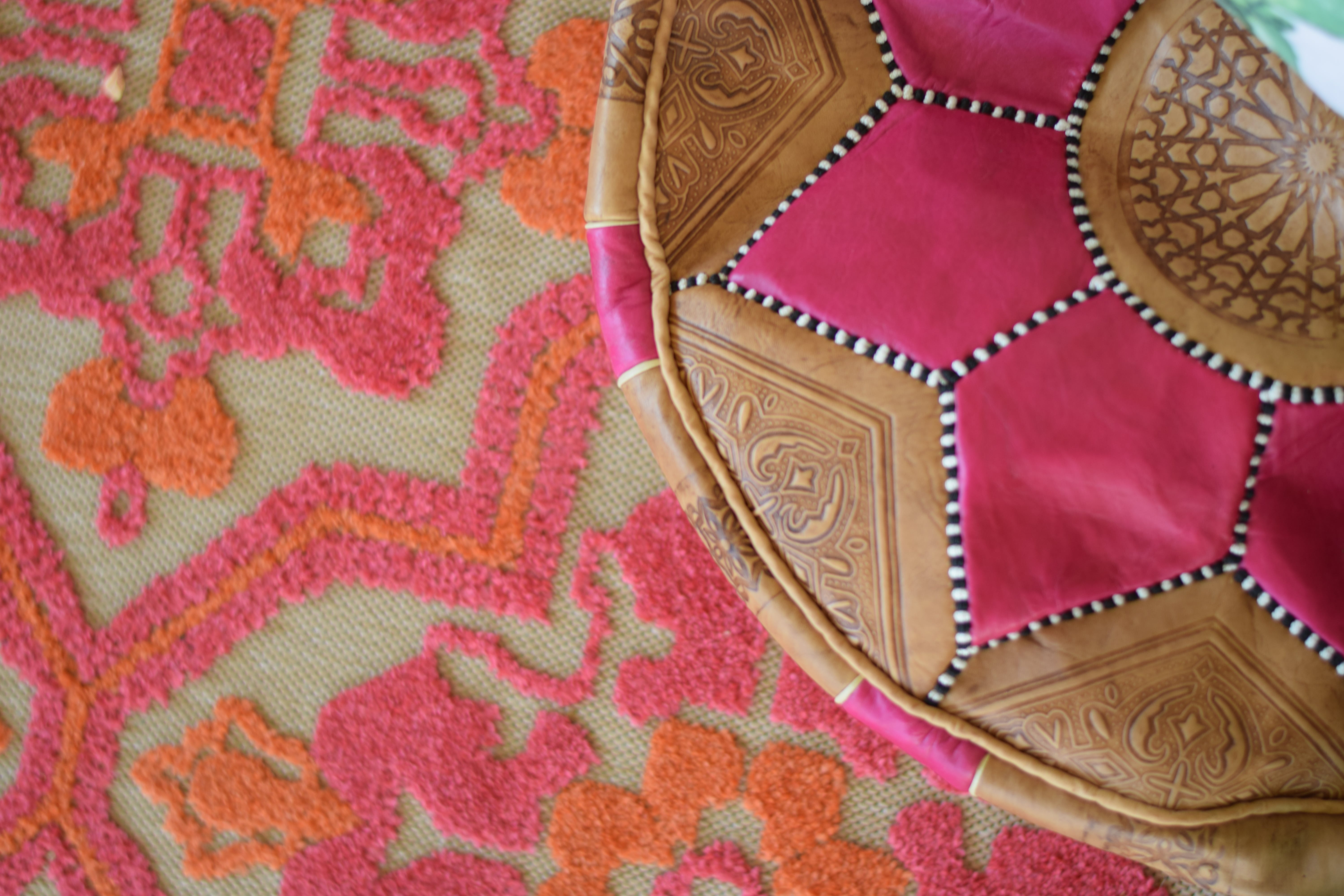 Leather pouf on pink and orange rug