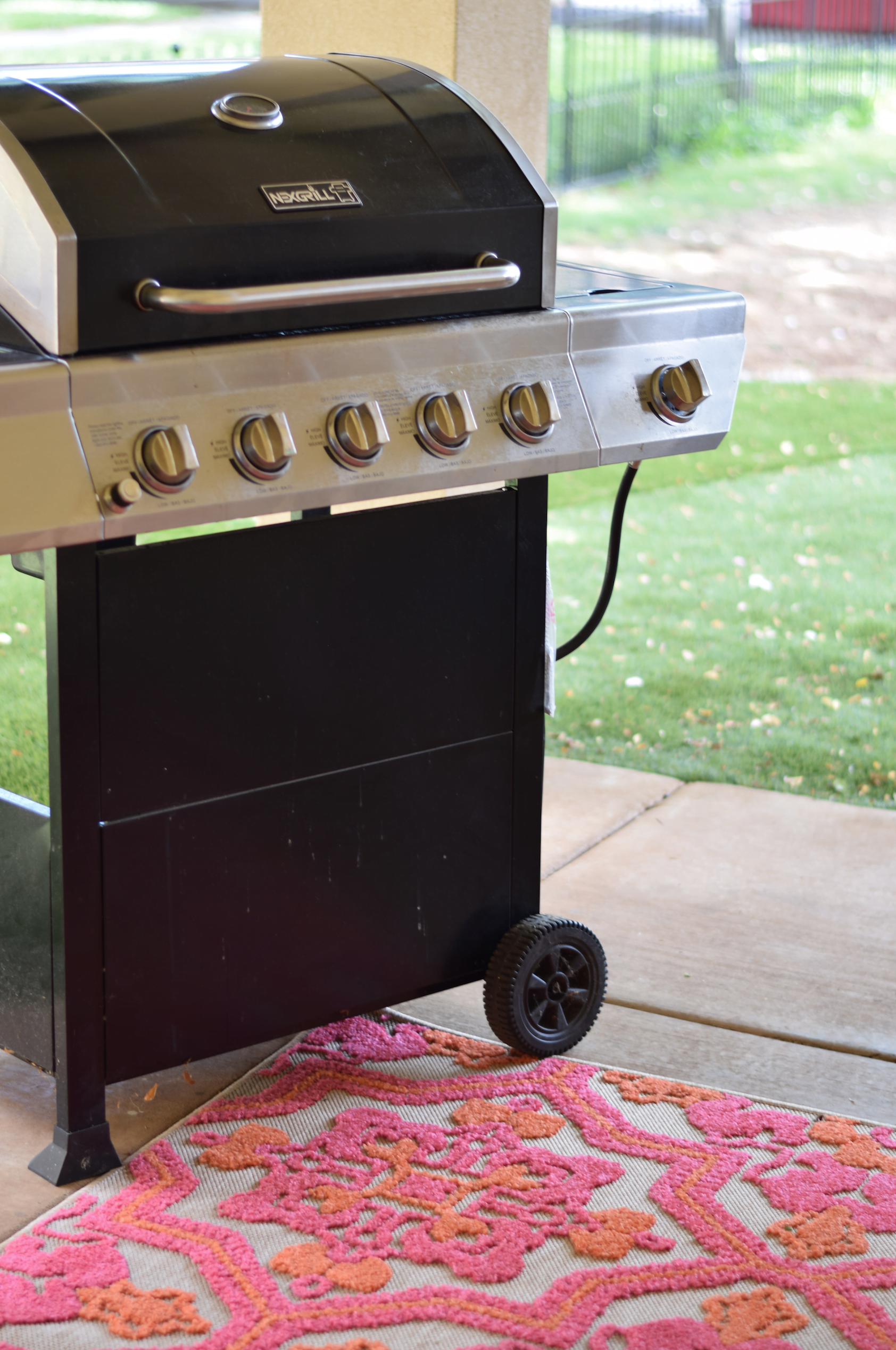 Outdoor grill on pink and orange outdoor rug. 