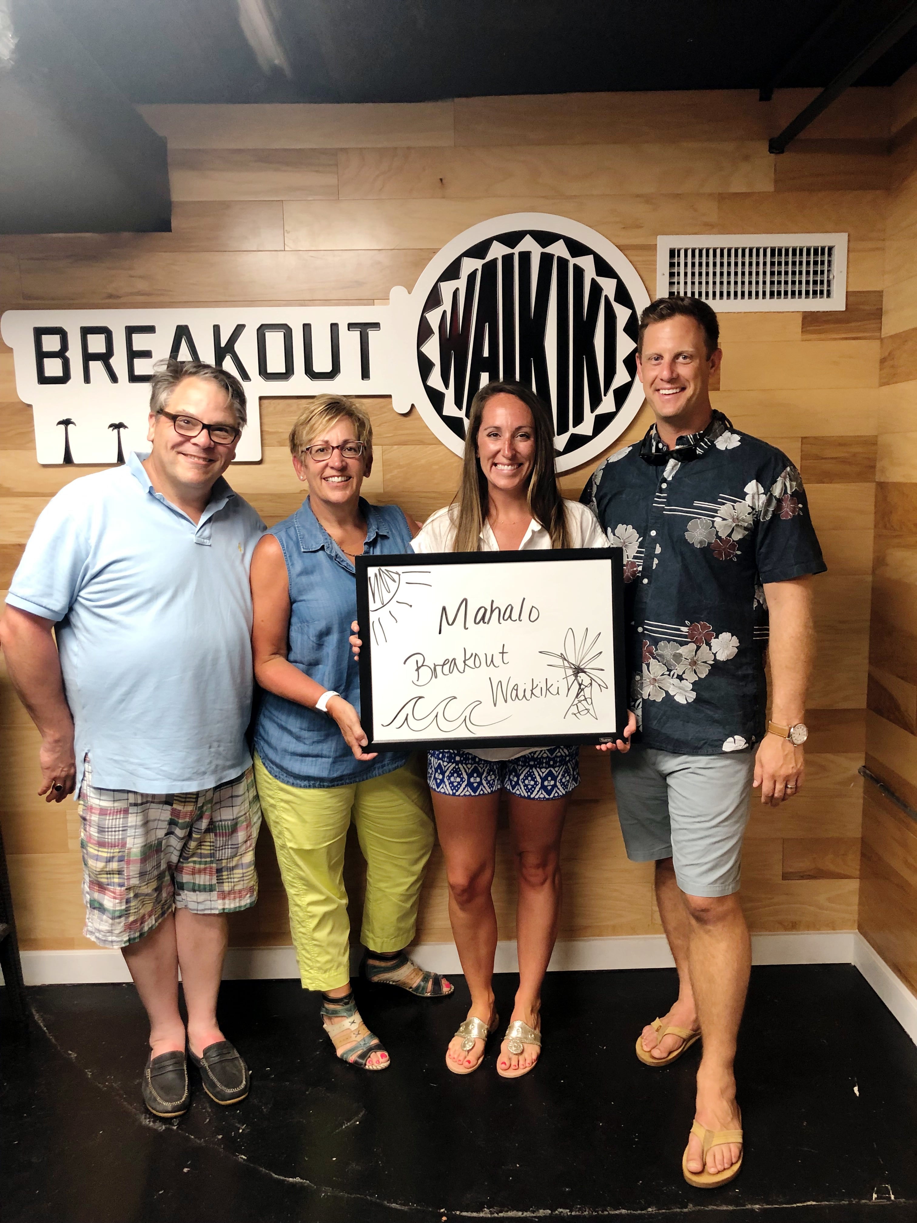 4 people standing against Breakout Waikiki Escape Room wall 